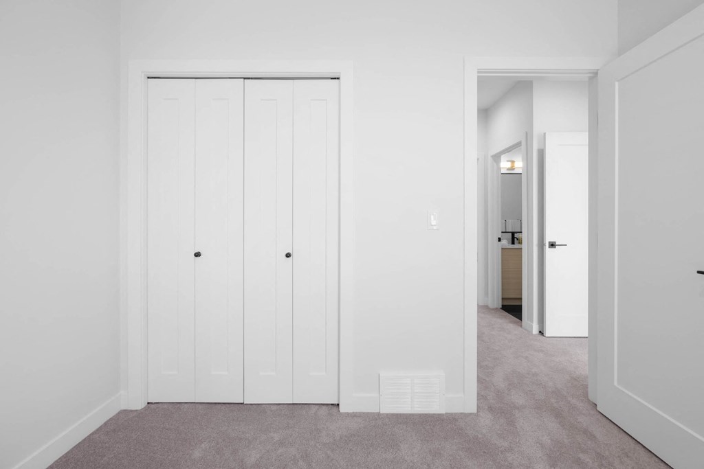 A white door with a black handle is in a room with a grey carpet.