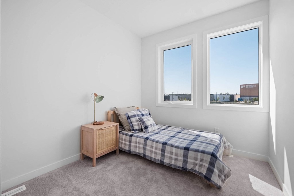 A bedroom with a bed, a nightstand, and a window.
