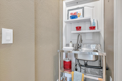 A small kitchen sink with a red container underneath it.