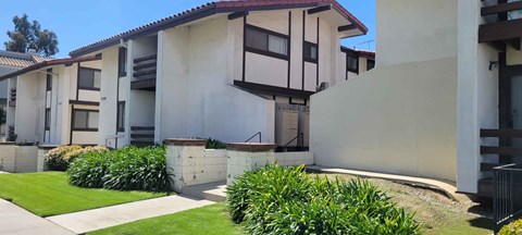 A white building with a red roof and a green lawn in front.