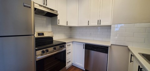 A kitchen with white cabinets and a stainless steel refrigerator.