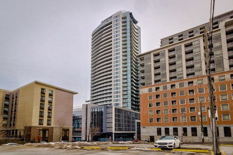 A tall building with many windows stands in front of a smaller building.