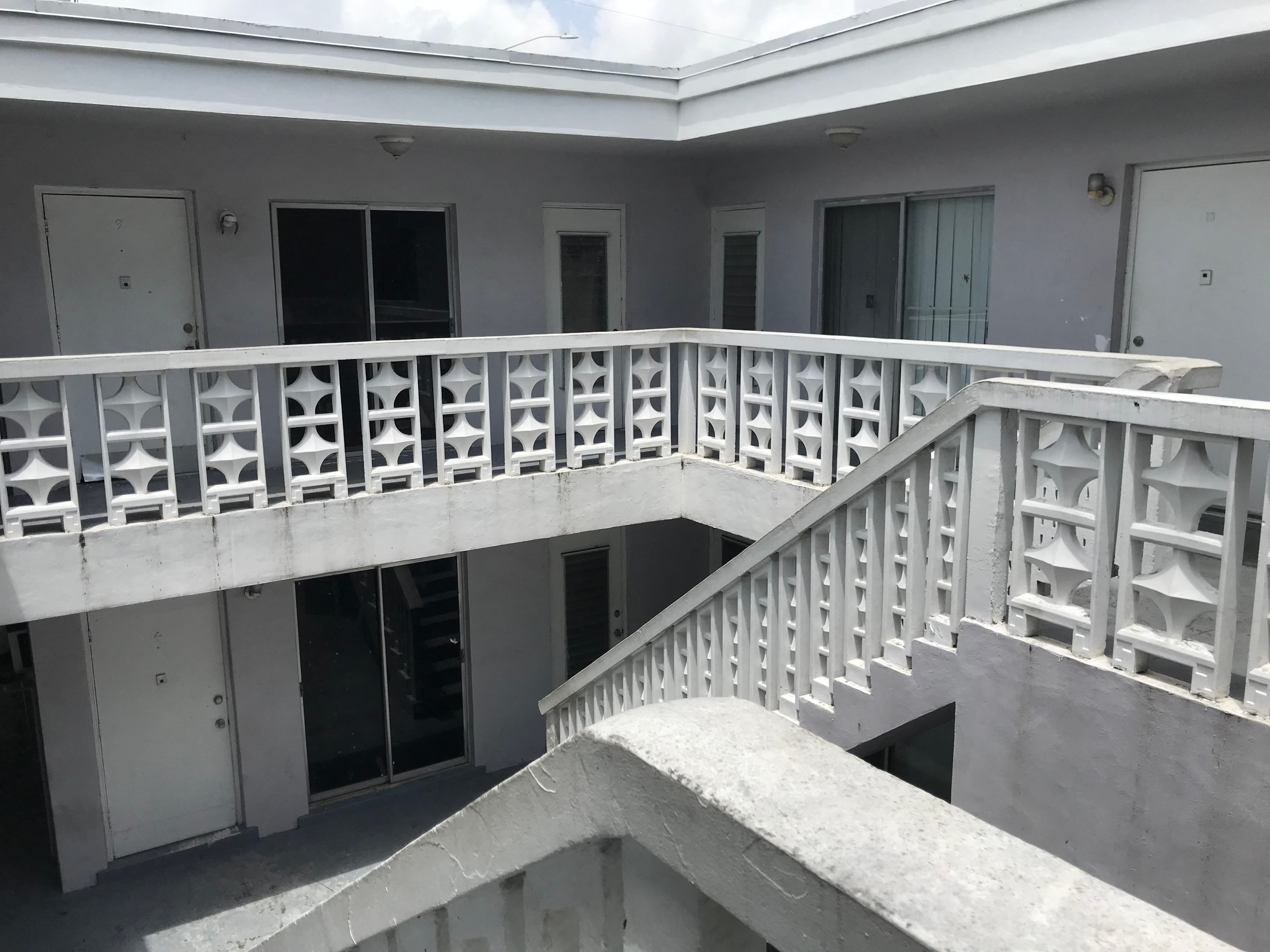 A white balcony with a staircase leading to a second floor.