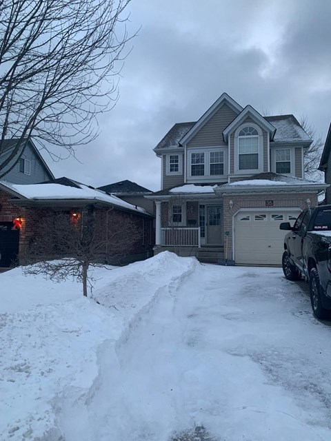 A house with a snow-covered driveway in front.