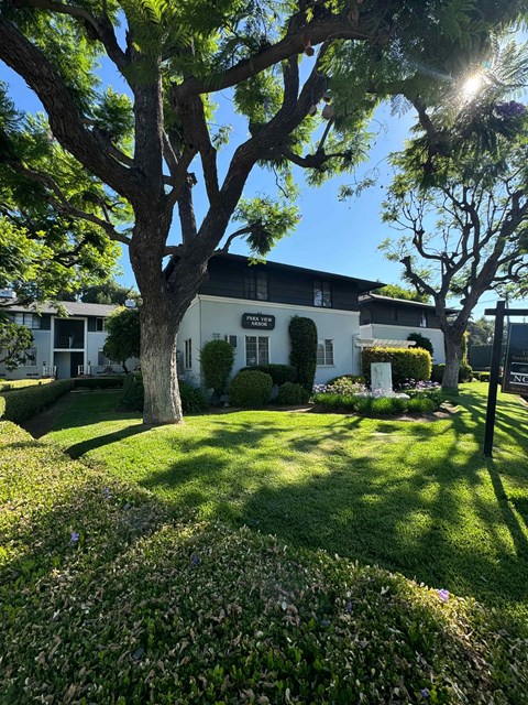 A white building with a black roof and a tree in front of it.