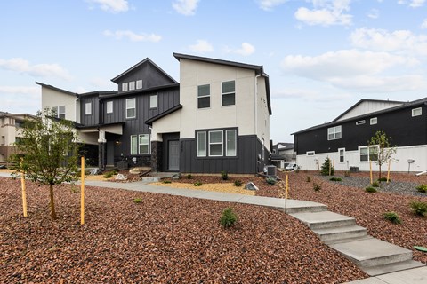 A modern house with a black and white exterior and a gravel garden in front.