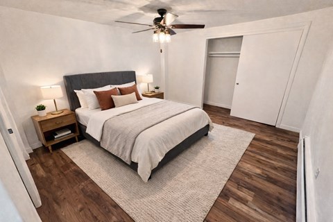 A bedroom with a bed, nightstand, and a ceiling fan.