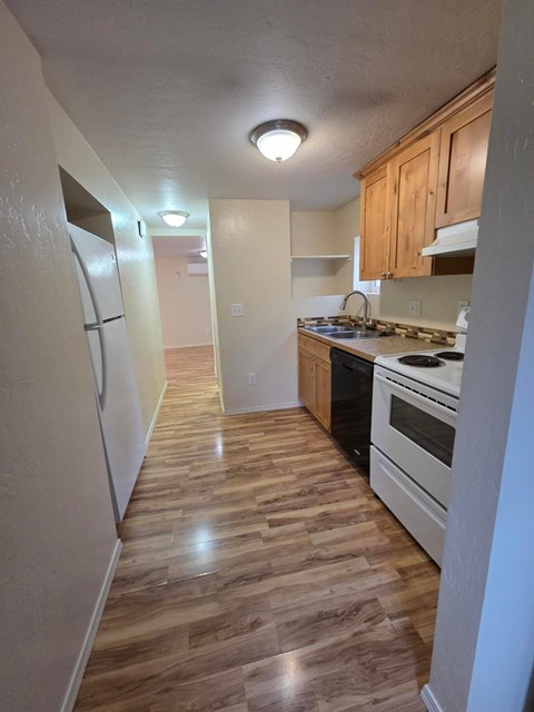 A kitchen with wooden floors and white appliances.