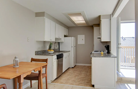 A kitchen with white cabinets and a wooden table.