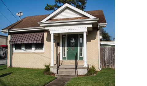 A small house with a green door and a porch.