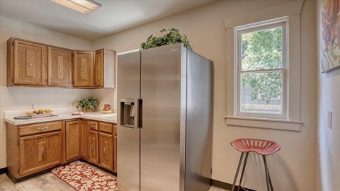 A kitchen with wooden cabinets and a stainless steel refrigerator.