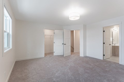 A spacious room with white walls and a carpeted floor.
