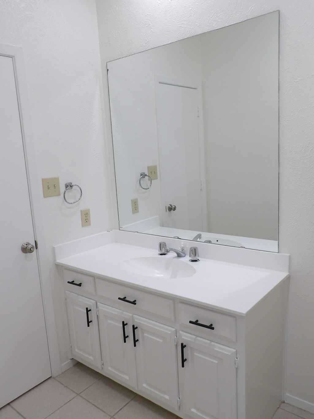 A white bathroom vanity with a sink and mirror.