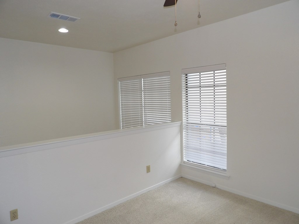 A room with a window covered by white blinds.