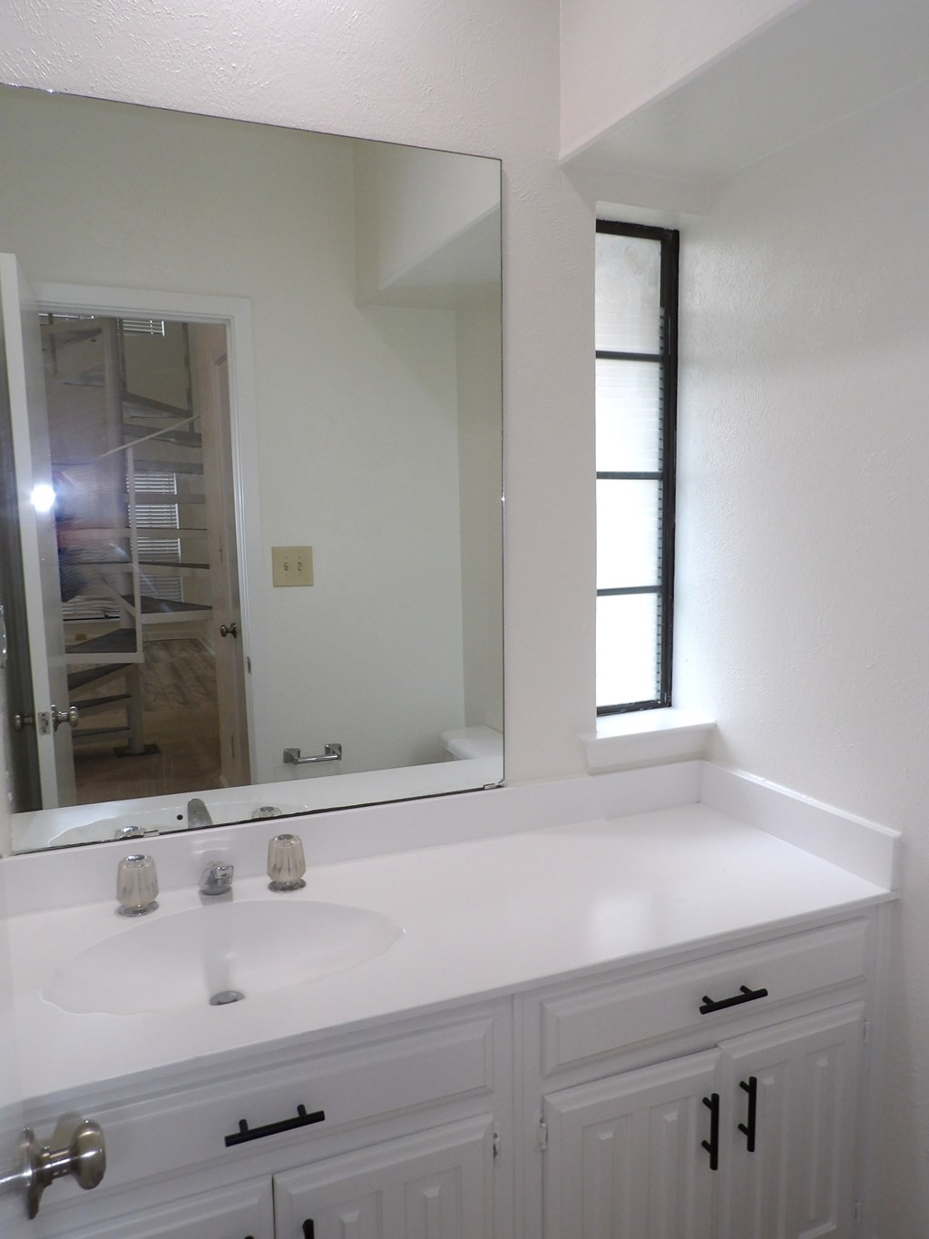 A white bathroom with a sink and mirror.