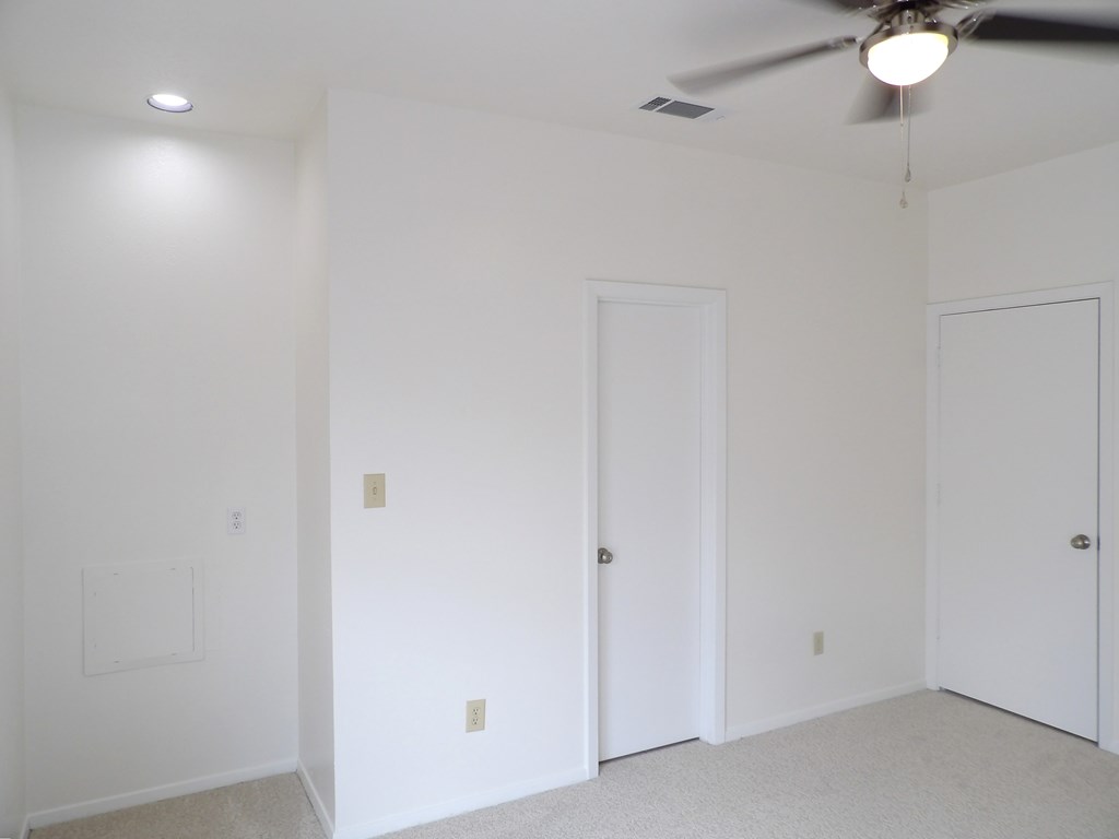 A room with a ceiling fan and two doors.