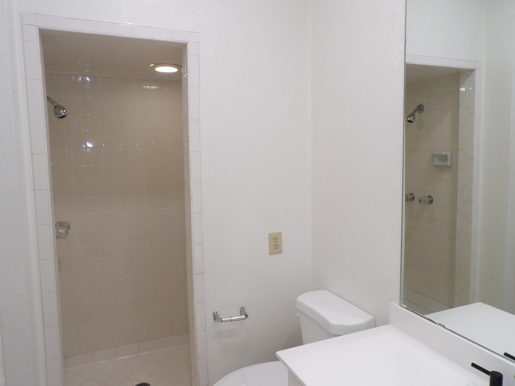 A white bathroom with a toilet, sink, and shower.