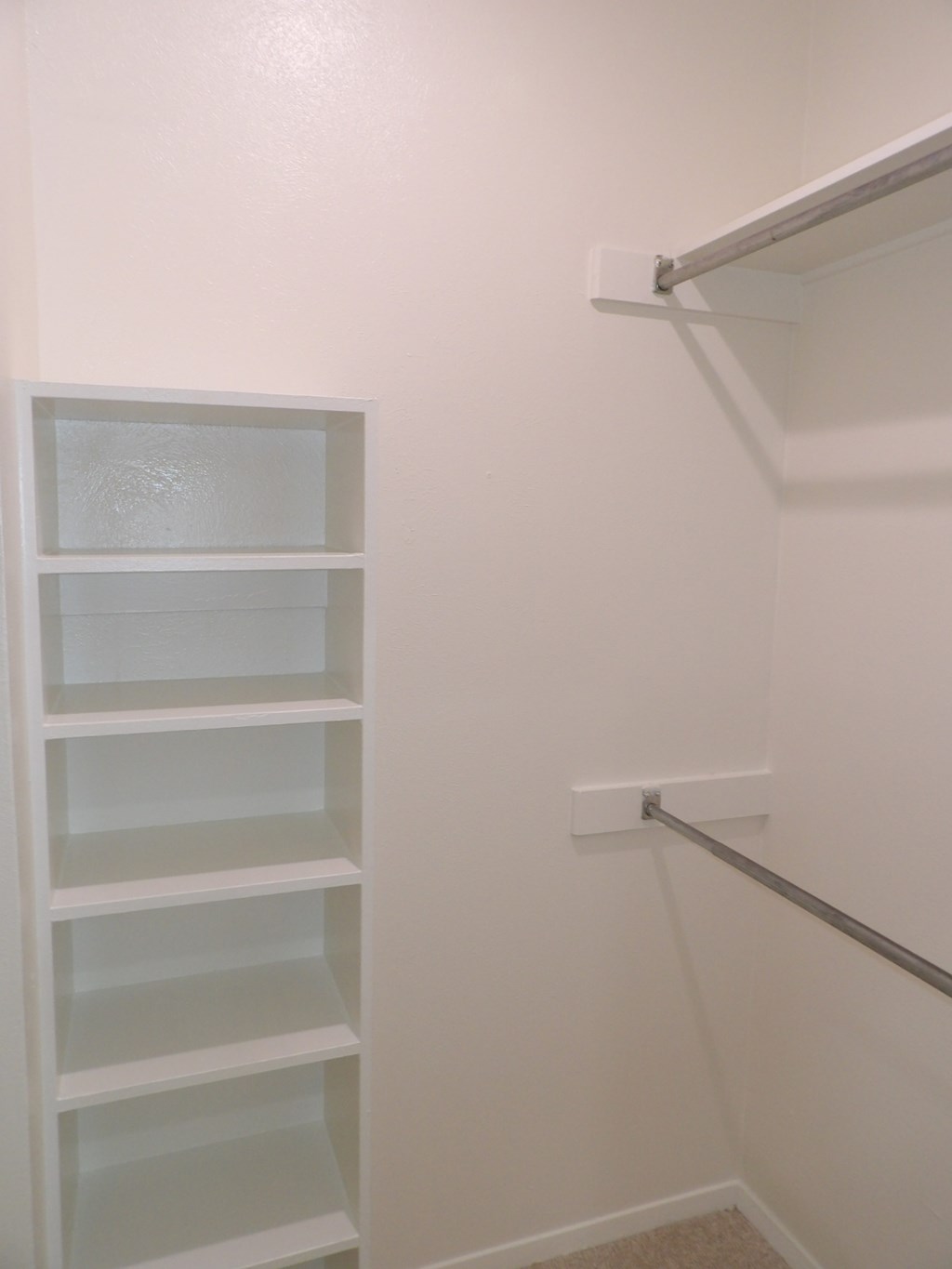 A white closet with shelves and a rod.
