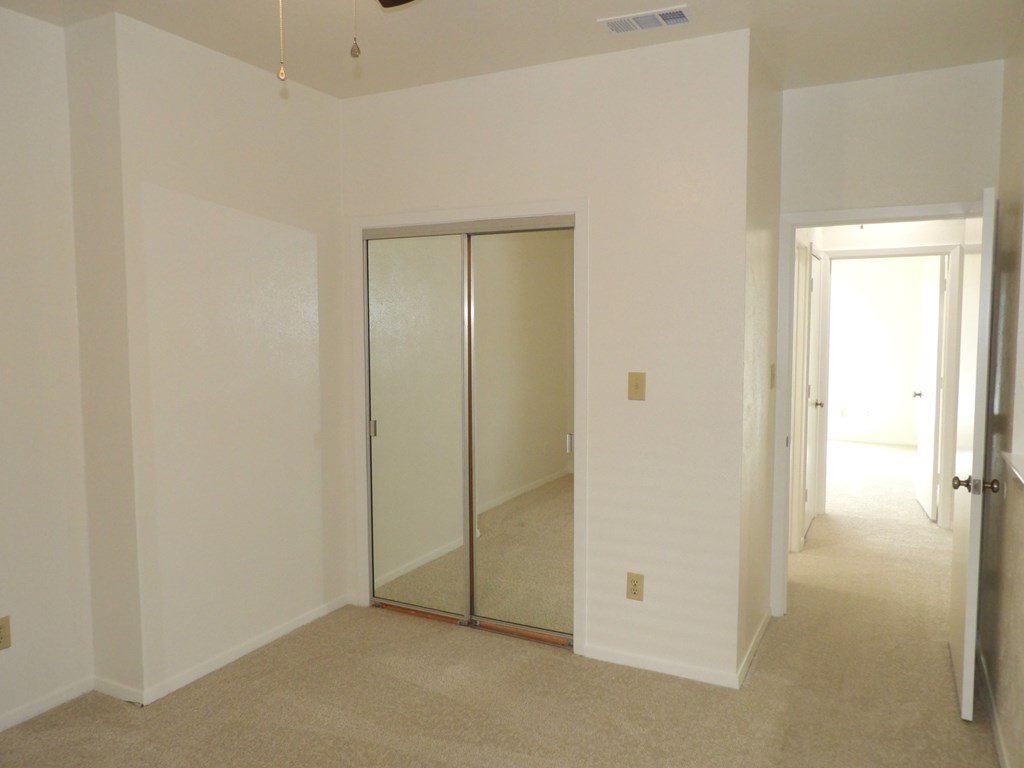 A room with a carpet floor and a sliding glass door.