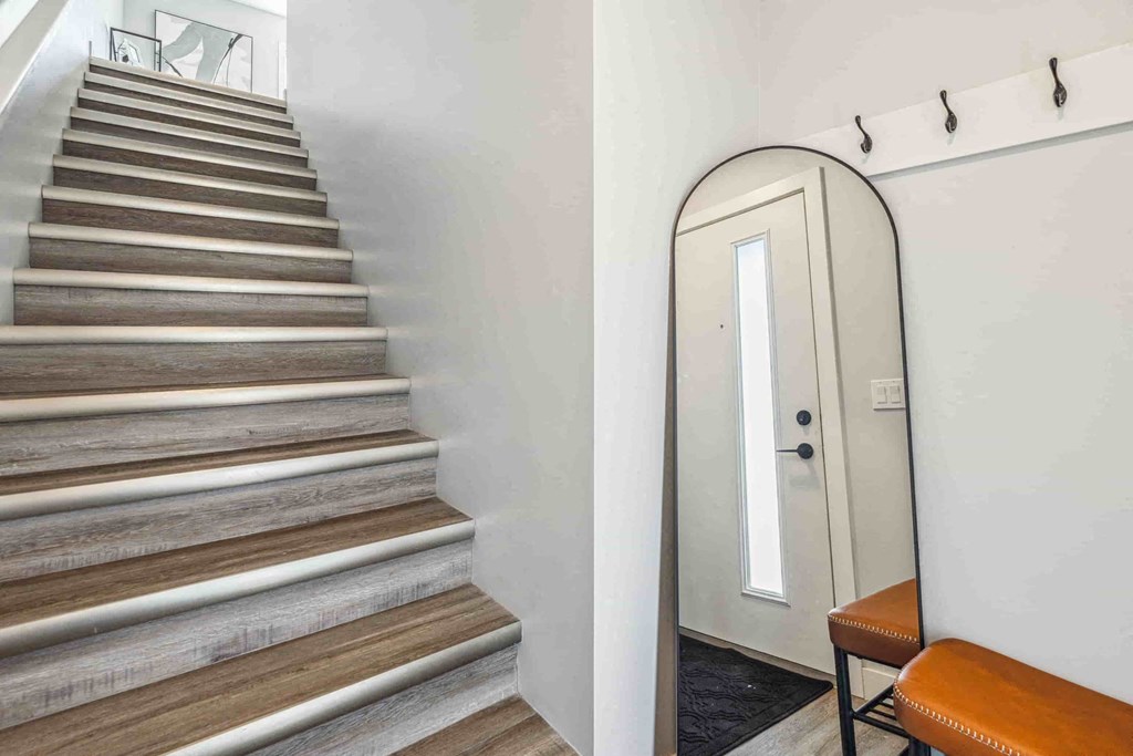 A staircase with a white wall and a mirrored door.