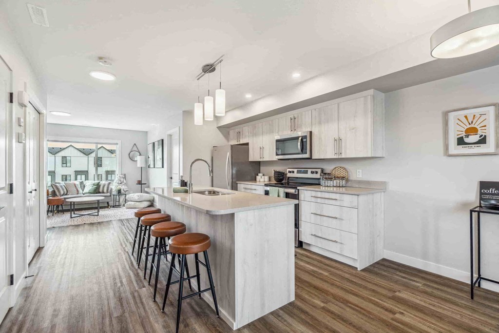 A kitchen with white cabinets and a bar area with stools.