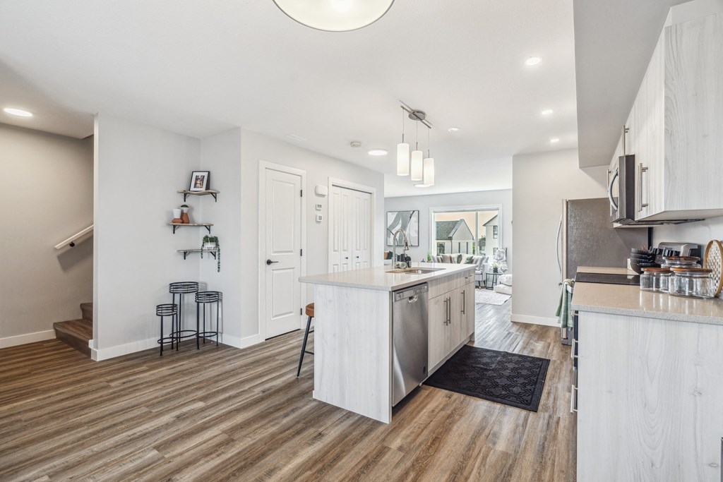 A kitchen with white cabinets and a wooden floor.