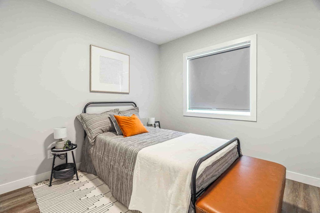 A bedroom with a bed, a small table, and a window.