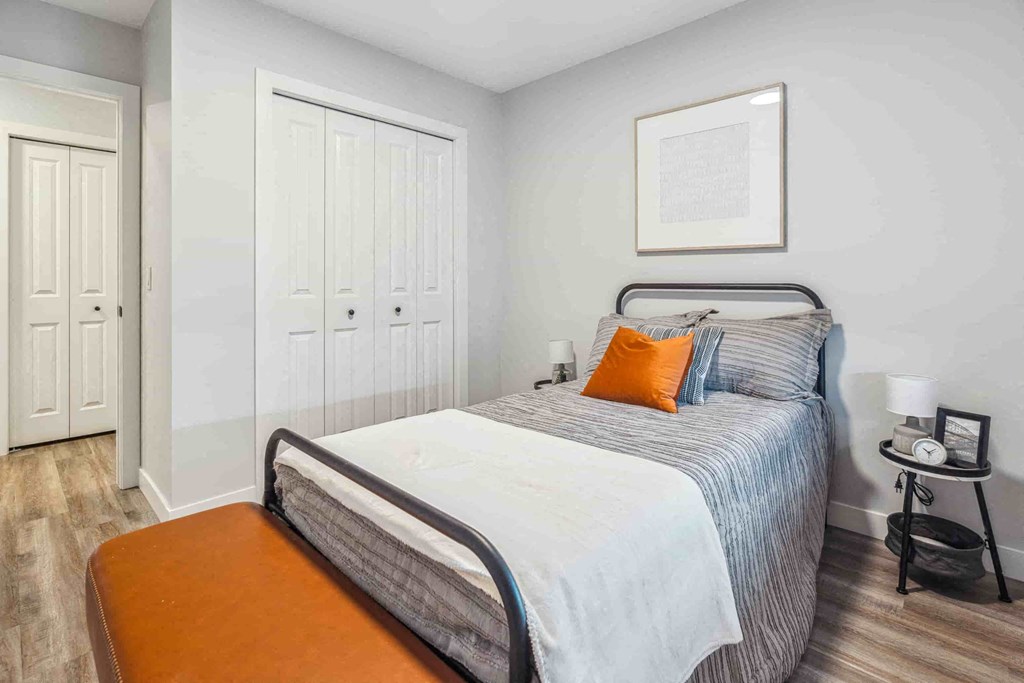 A bedroom with a bed, a nightstand, and a chair.