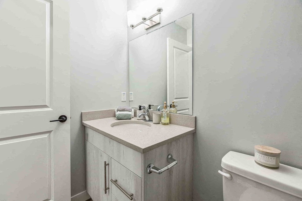 A bathroom with a white toilet and a white sink with a mirror above it.