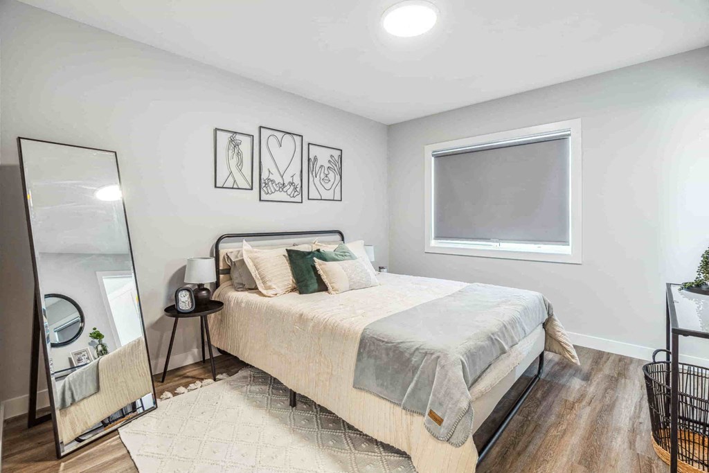 A bedroom with a bed, nightstand, and a mirror.