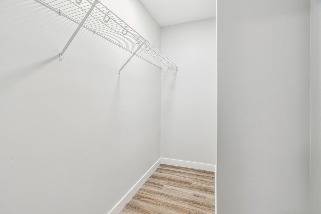 A white wall with a wooden floor and a clothes drying rack.
