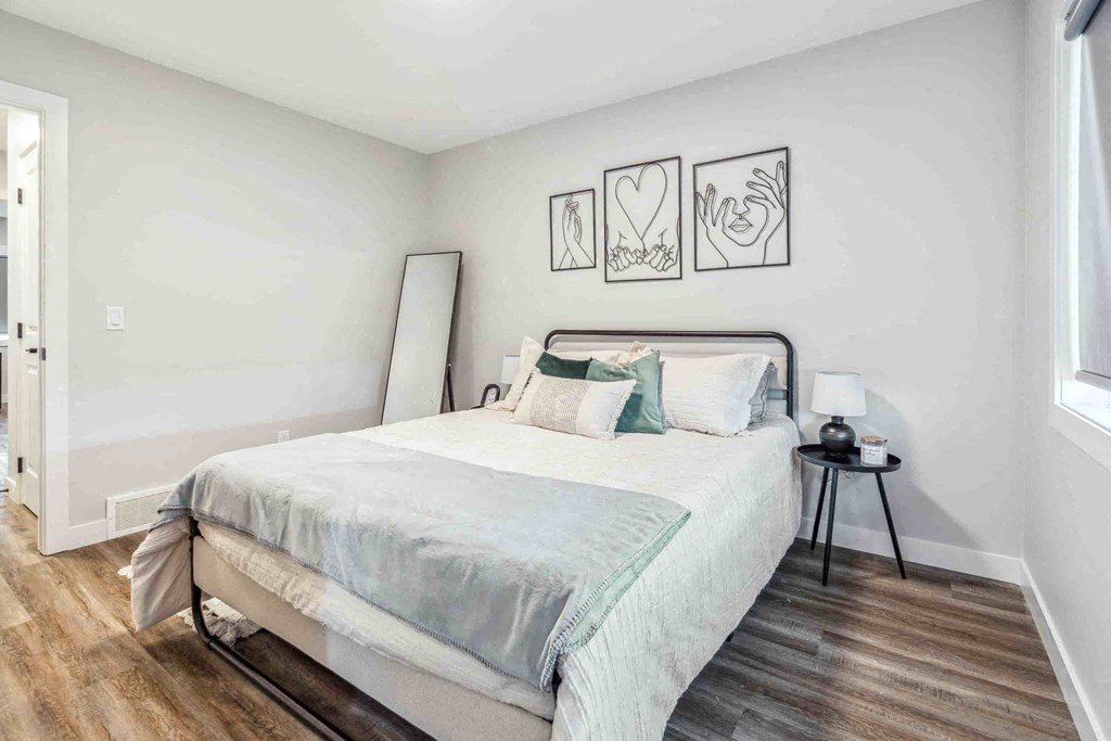 A bedroom with a bed, a lamp, and pictures on the wall.