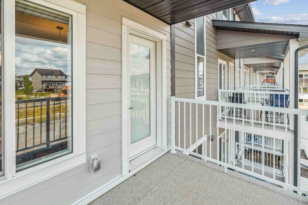 A balcony with a white railing and a view of a street with houses.