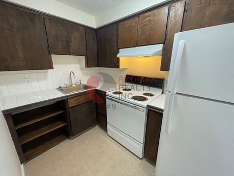 A kitchen with a white refrigerator, white stove, and brown cabinets.
