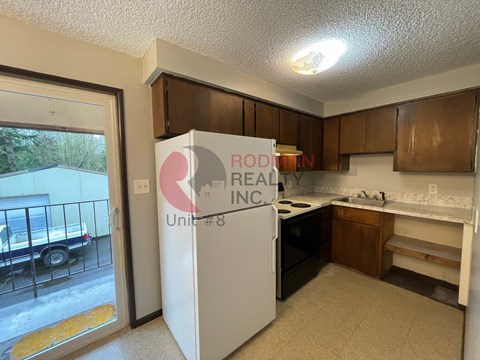 A kitchen with a refrigerator that says "RODIN REAL INC Unit #8".