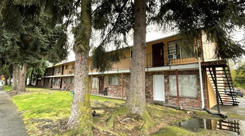 A building with a brown and beige exterior is surrounded by trees.
