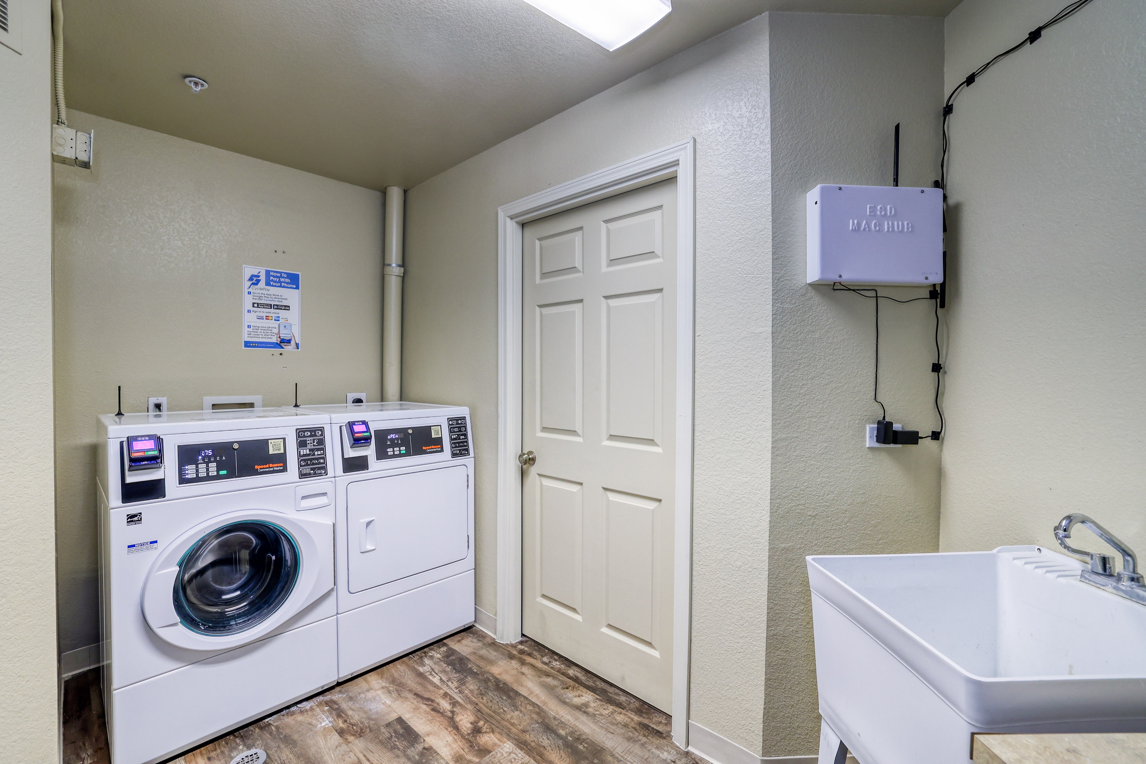 A laundry room with a washer and dryer, a sink, and a door.