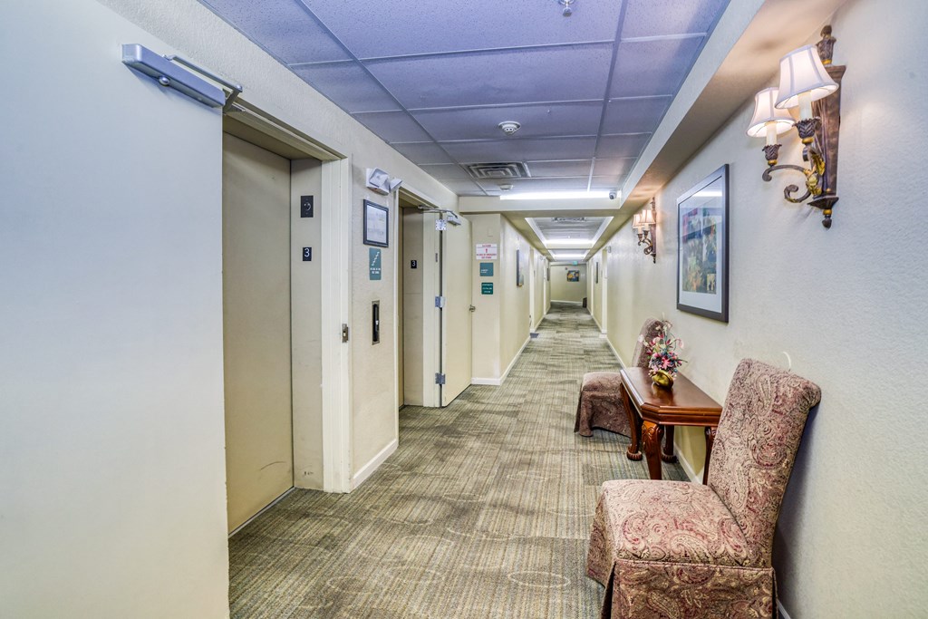 A hallway with chairs and a table on the right side.