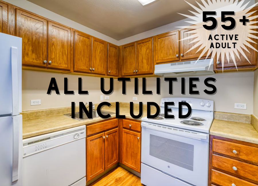 A kitchen with wooden cabinets and appliances, with a sign stating "55+ active adult" and "all utilities included".