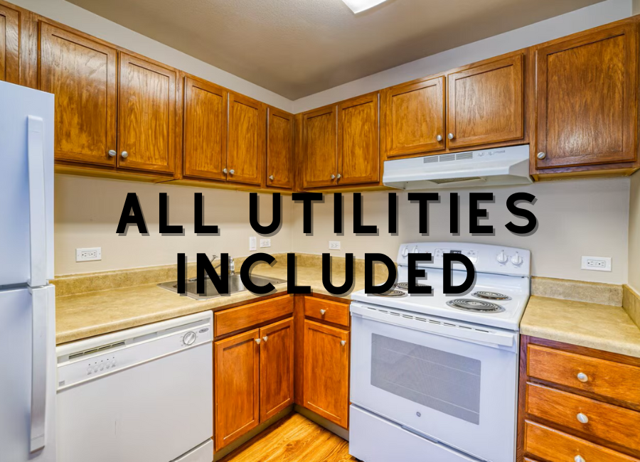 A kitchen with wooden cabinets and appliances, with text that reads "ALL UTILITIES INCLUDED".