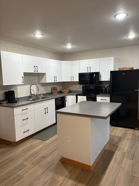 A kitchen with black appliances and white cabinets.
