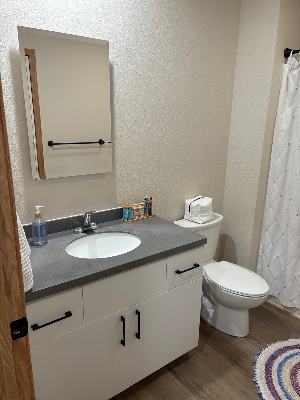 A bathroom with a sink, toilet, and a mirror.
