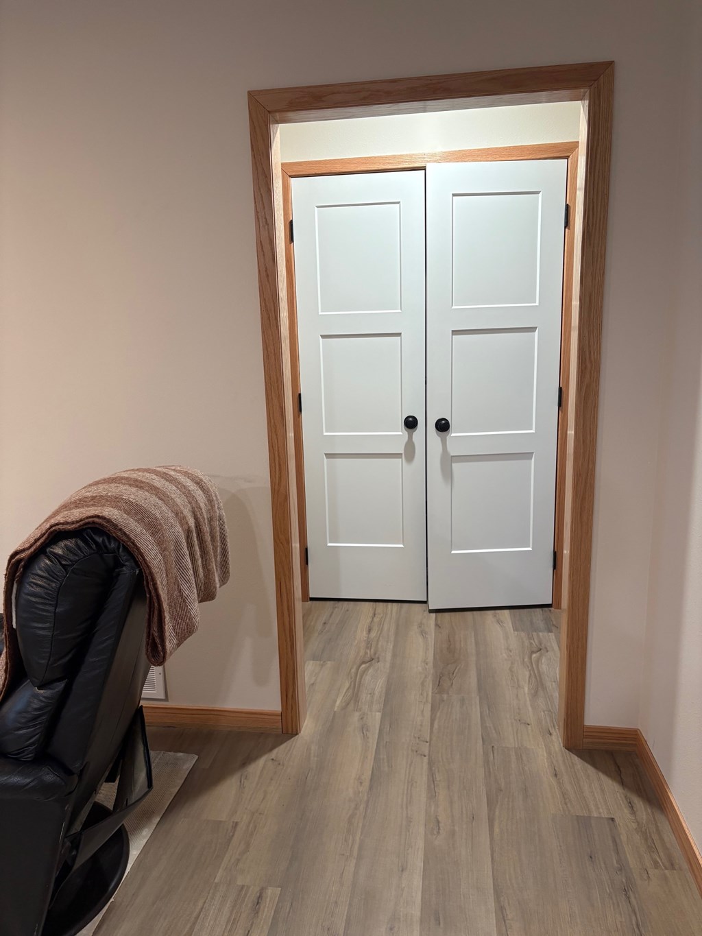 A white door with a black chair and a brown blanket in front of it.