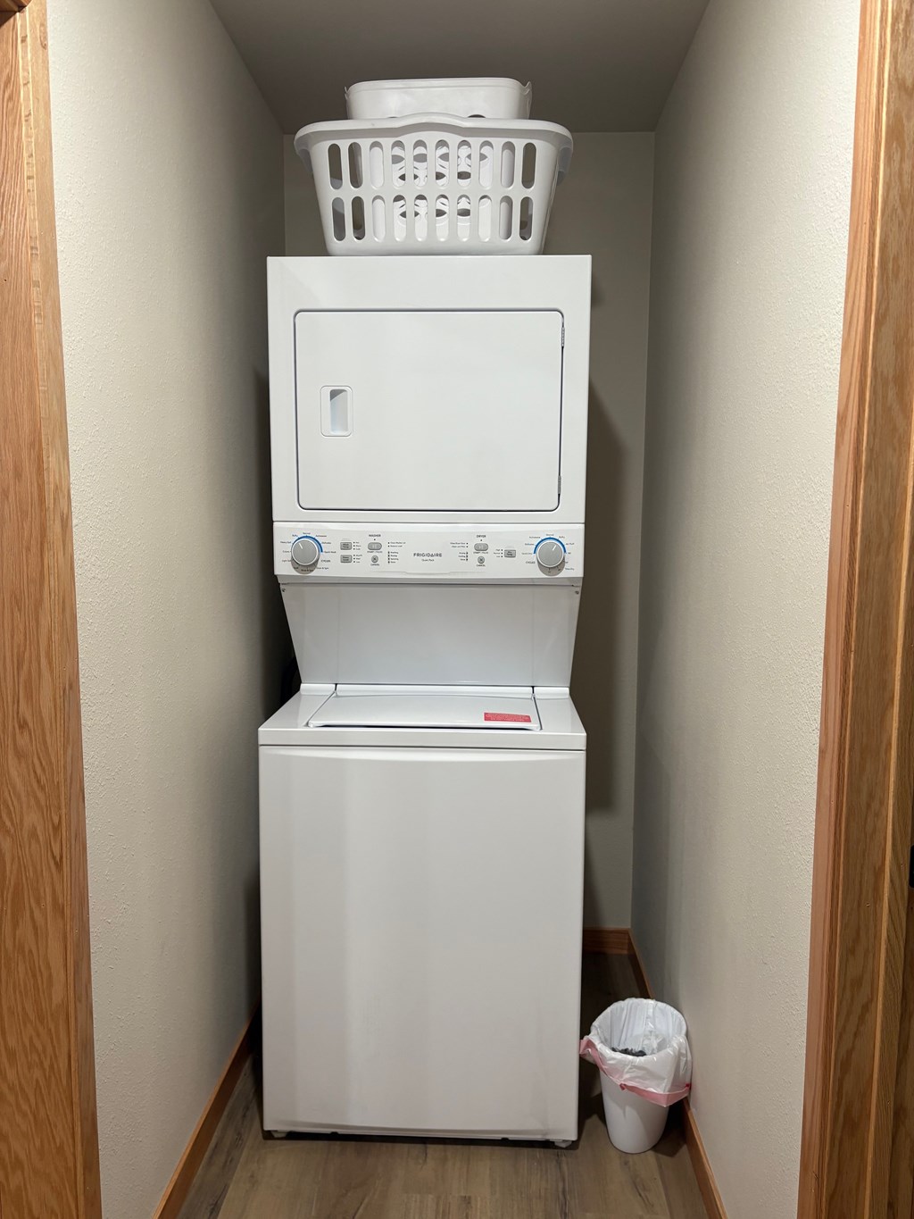 A white dishwasher with a basket on top is in a narrow hallway.
