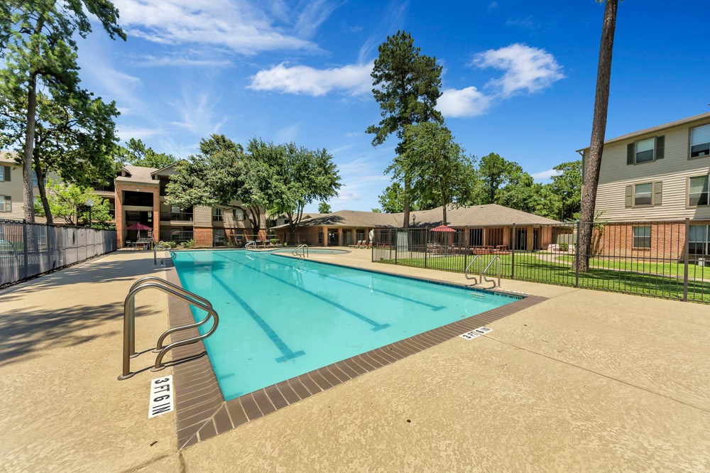 A swimming pool surrounded by a fence and trees.