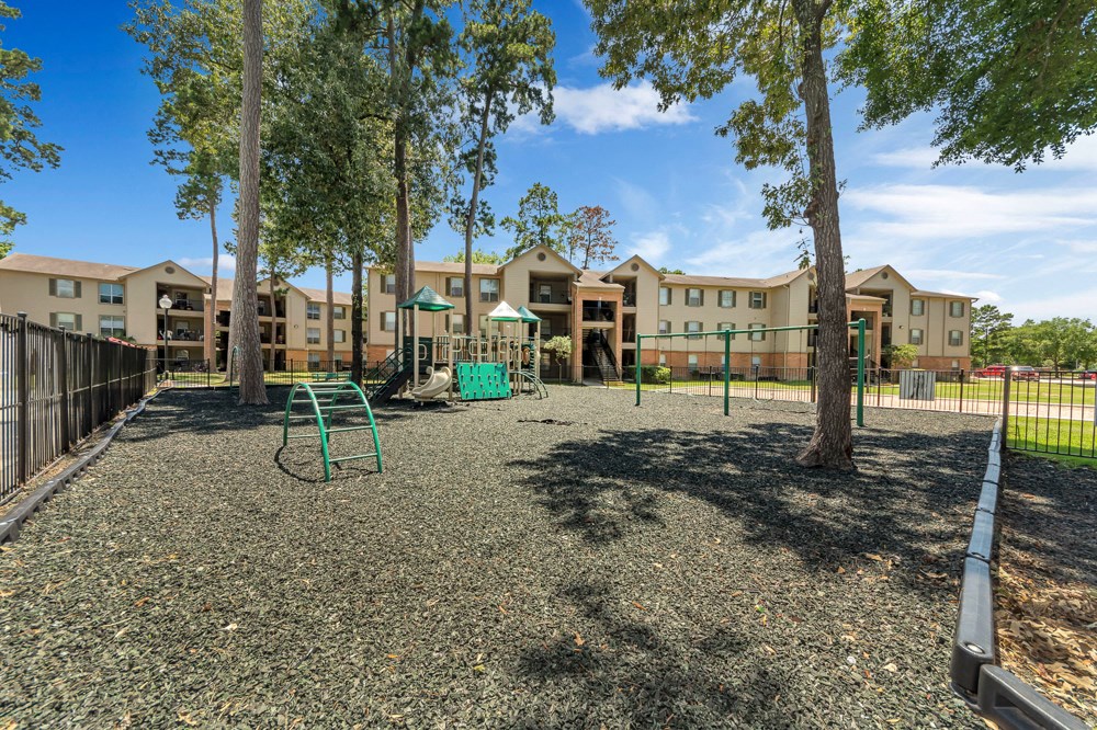 A playground area with a green slide and a play area in front of apartment buildings.
