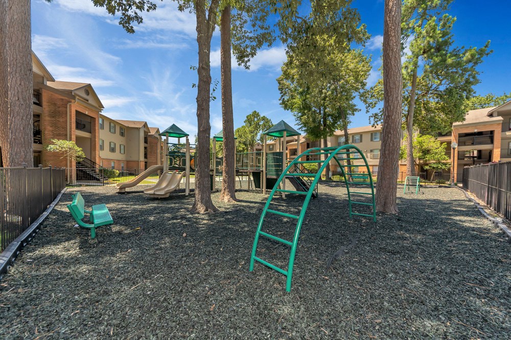 A playground with a green slide and a green bench.