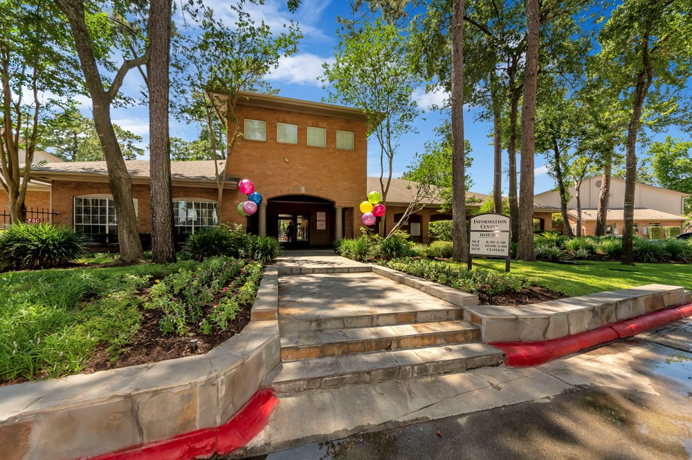 A building with a red brick facade and a sign that reads "Covenant" is surrounded by trees and greenery.