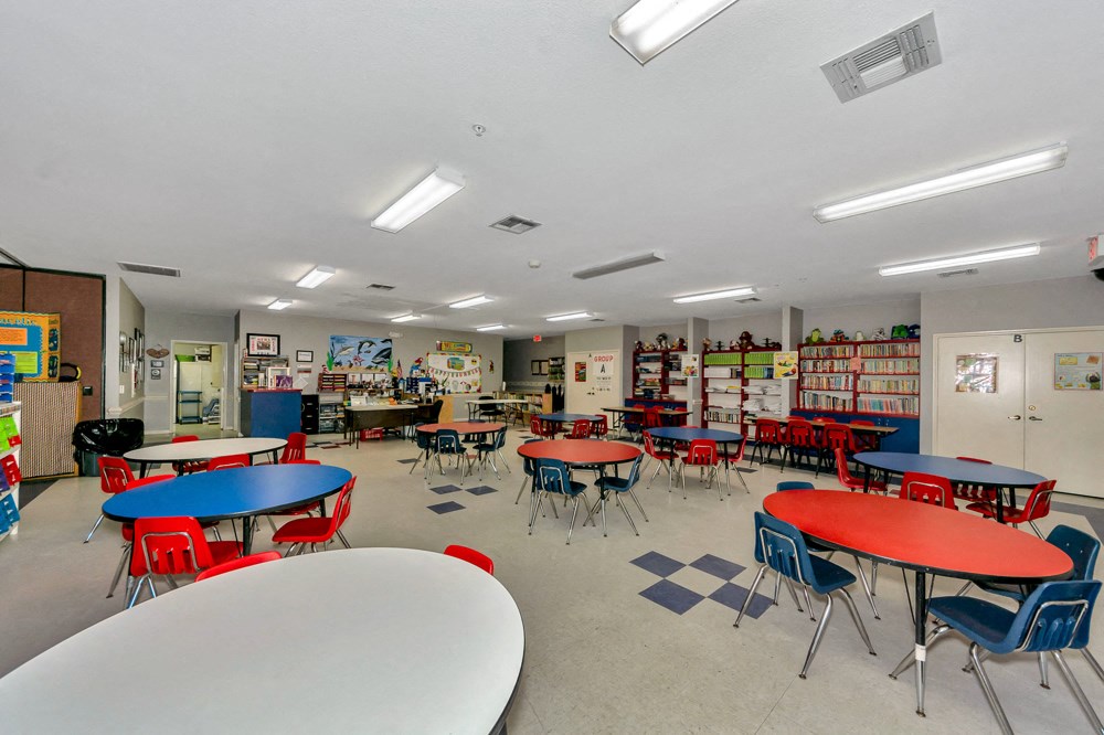 A classroom with tables and chairs and a whiteboard.