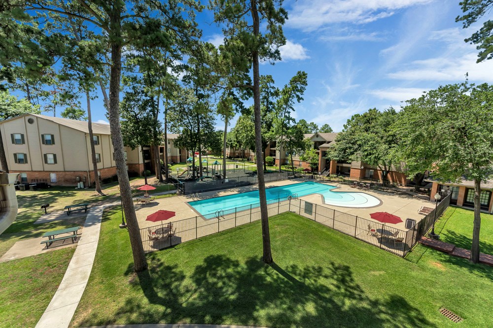 A pool surrounded by trees and a fence.